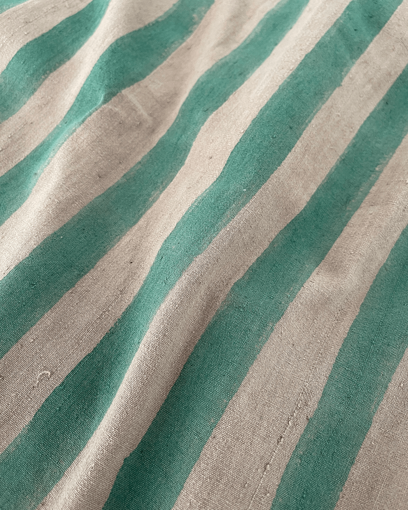 A handmade artisan blanket naturally dyed and handwoven with block-printed fabric in green and tan stripes.