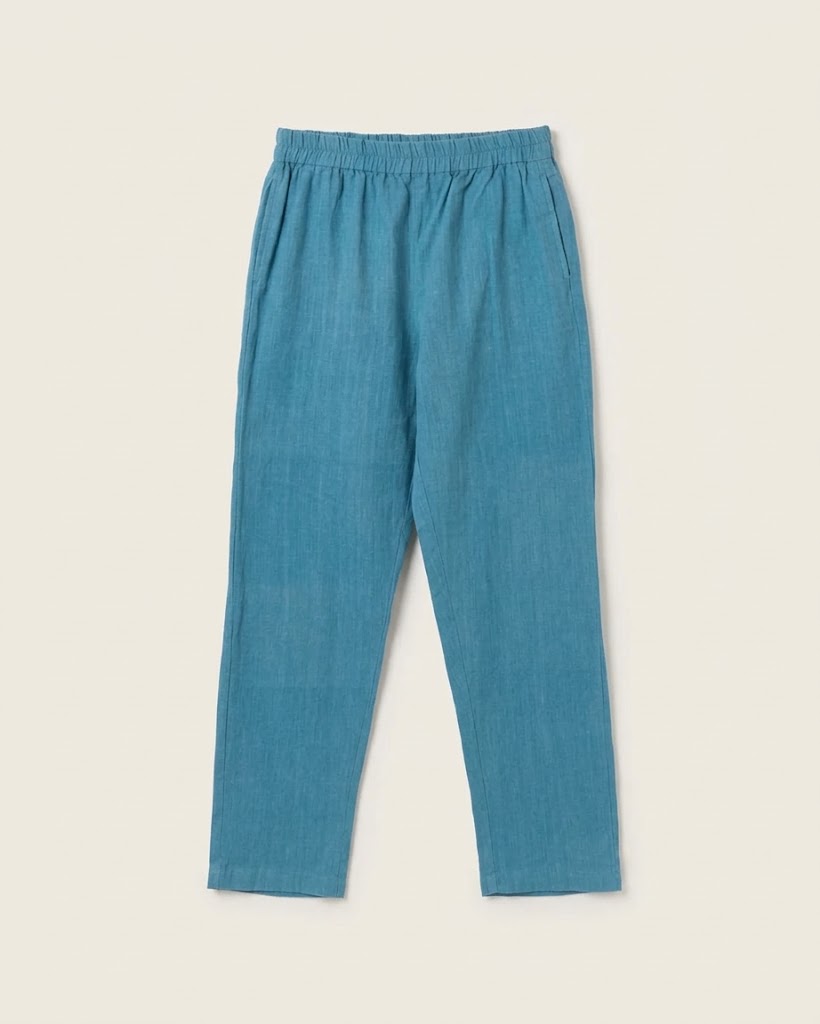 A pair of relaxed-fit, cropped pants in a textured teal blue fabric, featuring an elastic waistband and side pockets, displayed flat against a light beige background.
