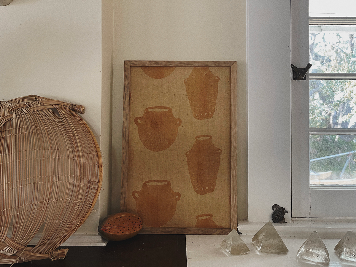 Decorative wall art with brown pottery design on a beige background, next to a woven basket and glass pyramids.