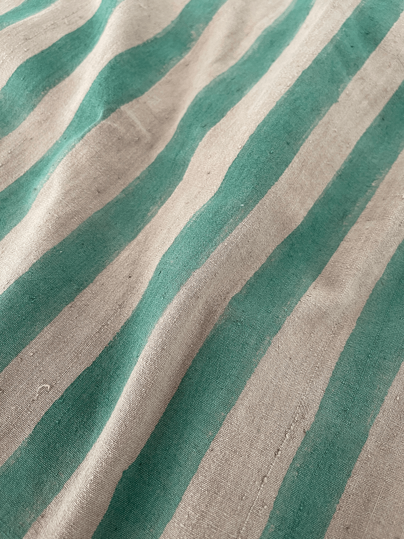 A handmade artisan blanket naturally dyed and handwoven with block-printed fabric in green and tan stripes.