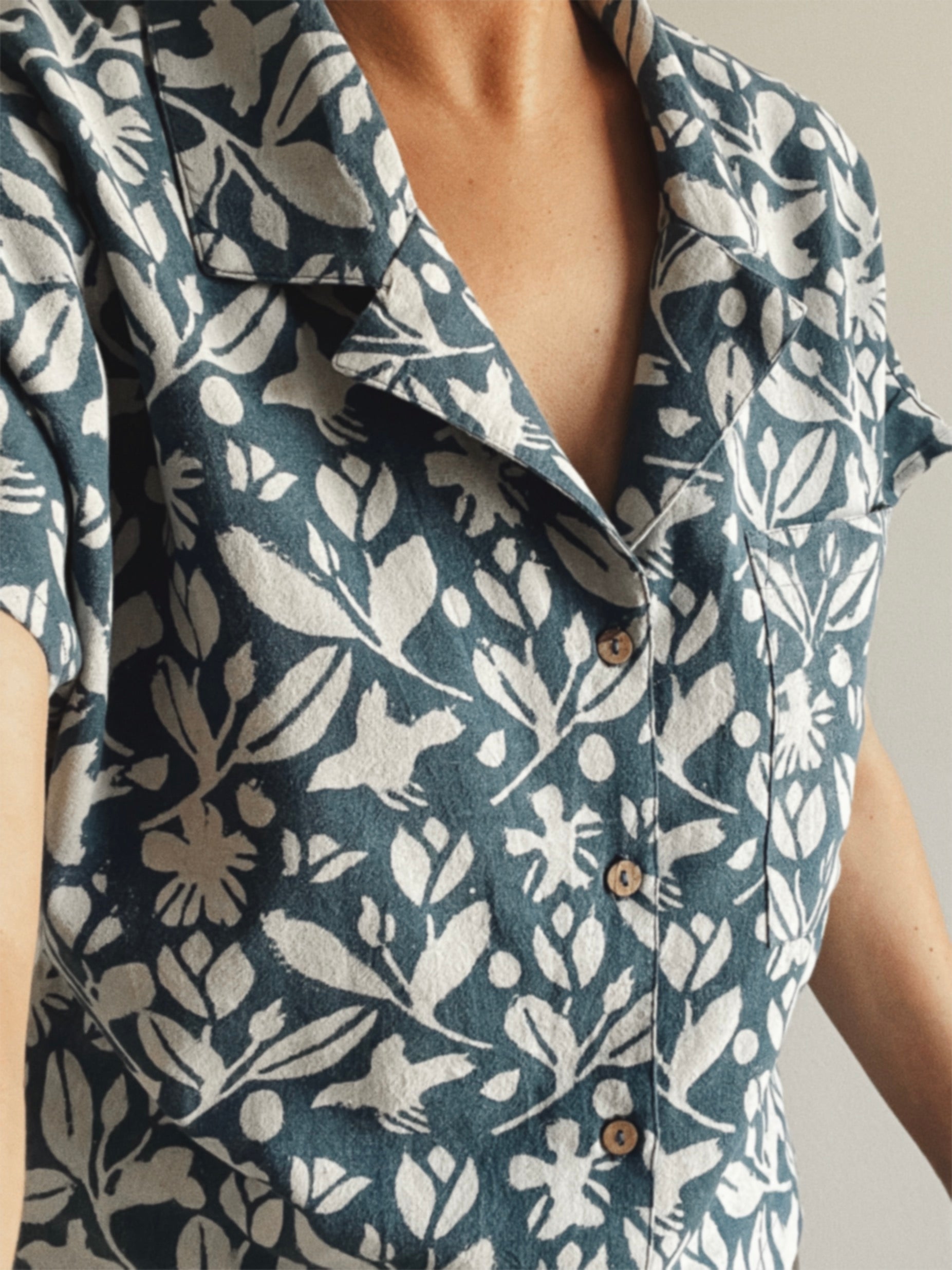 Close-up of a person wearing a floral patterned shirt with a neutral background