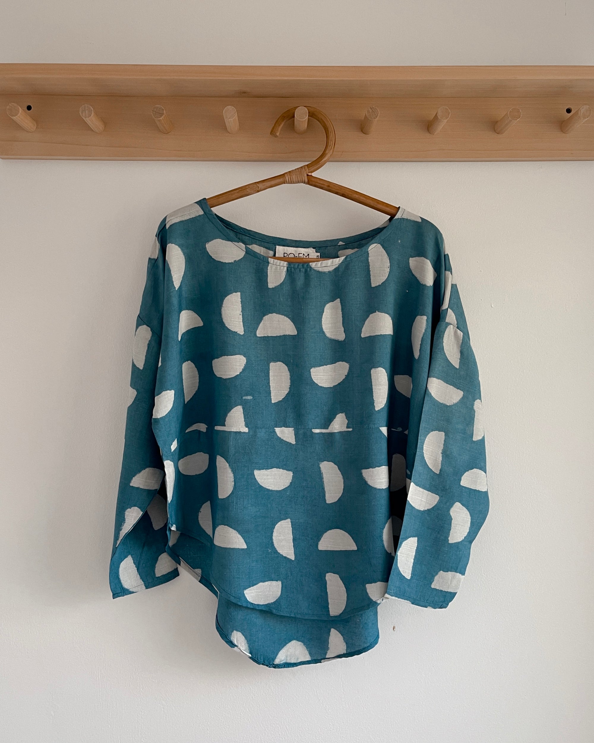 PO-Em Indigo Silky Sera Top in Setting Suns print hanging on a wooden hanger